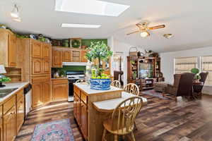Kitchen featuring light countertops, open shelves, dark wood finished floors, a center island, and vaulted ceiling