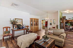 Living area featuring a chandelier, wood finished floors, and vaulted ceiling