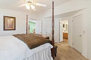 Bedroom with light colored carpet, ensuite bathroom, and a ceiling fan