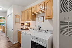 Laundry room with arched walkways, a heating unit, cabinet space, dark wood-style flooring, and washing machine and clothes dryer