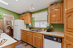 Kitchen featuring light countertops, white appliances, dark wood-style floors, and arched walkways