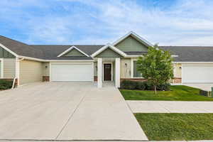 View of front of home with roof with shingles, a garage, concrete driveway, stone siding, and board and batten siding