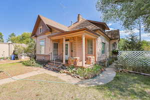 View of front of house featuring a porch, a front lawn, a chimney, and roof with shingles