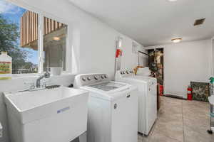 Washroom with washing machine and clothes dryer and light tile patterned floors