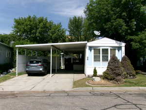 View of parking / parking lot with concrete driveway and a carport