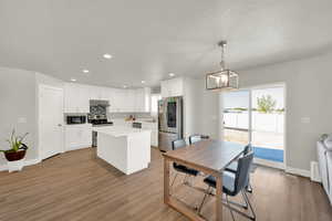 Kitchen featuring appliances with stainless steel finishes, a kitchen island, light wood-style floors, white cabinets, and a textured ceiling