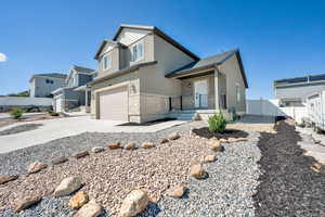 View of front facade with stone siding, stucco siding, concrete driveway, an attached garage, and covered porch