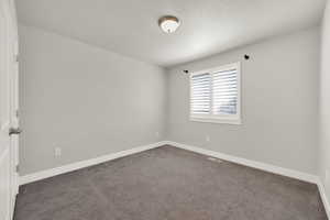 Spare room with dark carpet and a textured ceiling