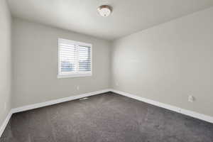 Spare room with dark colored carpet and baseboards