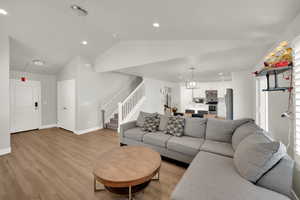 Living area with recessed lighting, lofted ceiling, light wood finished floors, and stairs