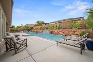 View of swimming pool featuring a patio, a fenced backyard, and a pool with connected hot tub