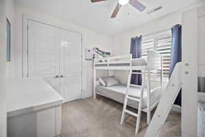 Bedroom featuring light carpet, a closet, and a ceiling fan