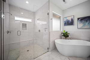Bathroom featuring plenty of natural light, tile walls, a shower stall, a soaking tub, and recessed lighting