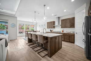 Kitchen with tasteful backsplash, a breakfast bar area, a kitchen island with sink, decorative light fixtures, and open floor plan