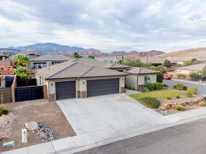 View of front facade featuring a garage, a mountain view, concrete driveway, and stone siding