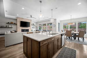 Kitchen with light wood-style flooring, hanging light fixtures, open floor plan, recessed lighting, and a tray ceiling