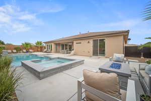 View of swimming pool with a patio area, a fenced backyard, a pool with connected hot tub, and an outdoor living space with a fire pit