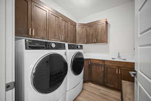 Laundry room with light wood finished floors, independent washer and dryer, and cabinet space