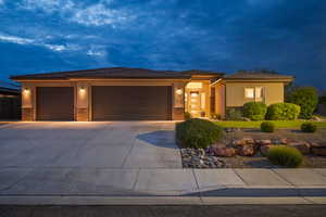 Prairie-style home featuring an attached garage, concrete driveway, stucco siding, a tiled roof, and stone siding