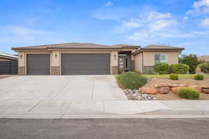 Prairie-style home with stucco siding, stone siding, a garage, and concrete driveway