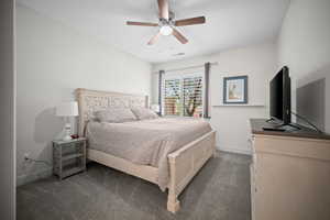 Bedroom with dark carpet and a ceiling fan