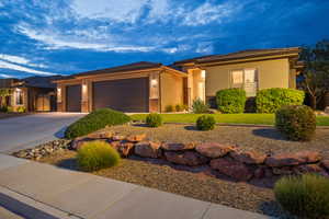Prairie-style house with a garage, stucco siding, driveway, a tile roof, and stone siding