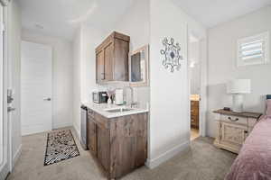 Kitchen featuring light carpet, stainless steel microwave, dark brown cabinets, and light stone counters