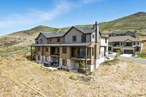 Rear view of house with stone siding, a mountain view, a shingled roof, a chimney, and a garage