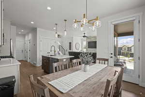 Dining room featuring a chandelier, recessed lighting, dark wood finished floors, ceiling fan, and a stone fireplace
