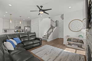 Living room with stairs, recessed lighting, light wood-style floors, and a ceiling fan