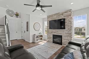 Living area featuring stairs, plenty of natural light, wood finished floors, a stone fireplace, and recessed lighting