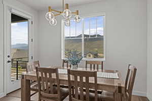 Dining area with a mountain view, healthy amount of natural light, wood finished floors, and a chandelier