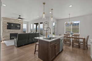 Kitchen with hanging light fixtures, dark brown cabinetry, light wood finished floors, recessed lighting, and a fireplace