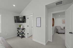 Hallway featuring light colored carpet, recessed lighting, and lofted ceiling
