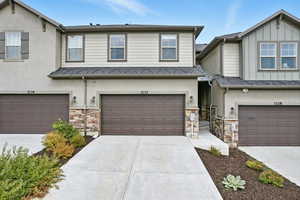 View of front of house featuring stone siding, driveway, stucco siding, and a garage