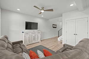 Living area with light wood-style flooring, a ceiling fan, recessed lighting, and stairway