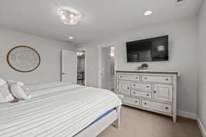 Bedroom featuring light colored carpet, recessed lighting, and ensuite bath