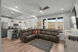 Living room featuring light wood-type flooring, beam ceiling, recessed lighting, and ceiling fan