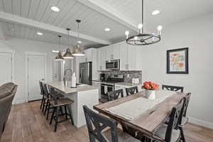 Dining space featuring beam ceiling, a chandelier, light wood-style flooring, and recessed lighting