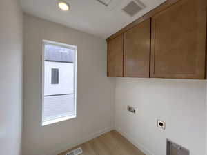 Washroom featuring light wood finished floors, cabinet space, hookup for an electric dryer, and washer hookup