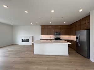 Kitchen with appliances with stainless steel finishes, a center island with sink, recessed lighting, open floor plan, and light wood-style flooring