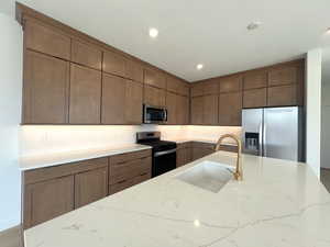 Kitchen with light stone countertops, stainless steel appliances, recessed lighting, and a textured ceiling