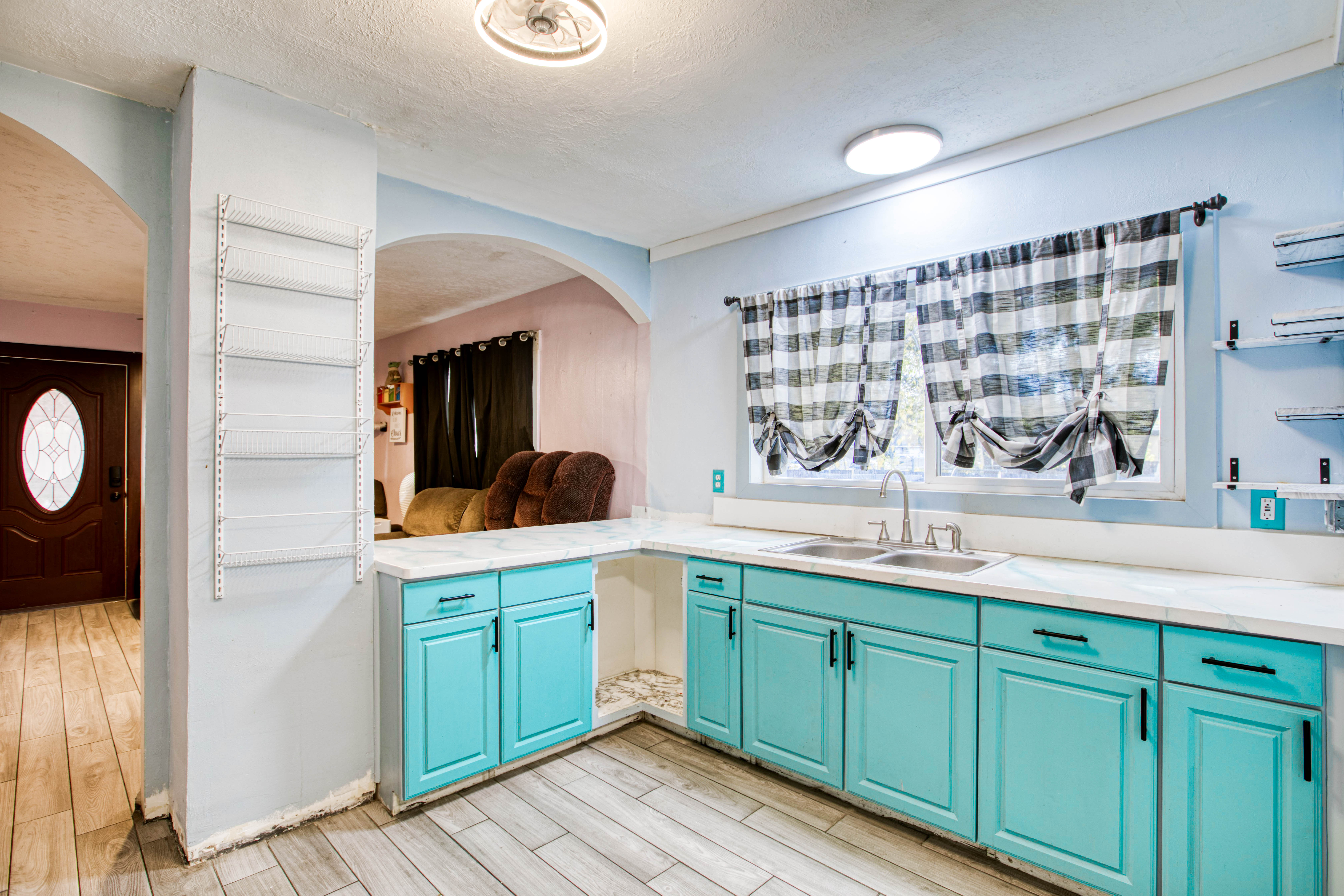Kitchen with a textured ceiling, light countertops, light wood-style flooring, open shelves, and arched walkways