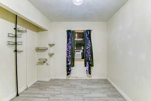 Empty room with wood tiled floors, a textured ceiling, and cooling unit