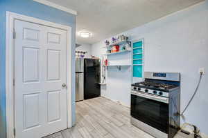 Kitchen featuring stainless steel range with gas cooktop, wood tiled floors, a textured ceiling, and open shelves