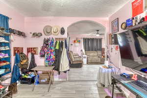 Living area featuring a textured ceiling, light wood finished floors, and arched walkways