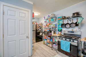 Kitchen with stainless steel appliances, light wood-type flooring, and a textured ceiling