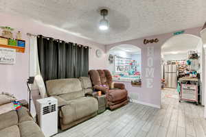 Living room featuring a textured ceiling, wood finish floors, and arched walkways