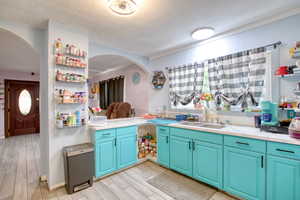 Kitchen with light countertops, a textured ceiling, wood tiled floors, open shelves, and arched walkways