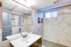 Bathroom with vanity, a shower stall, tile walls, and a textured ceiling